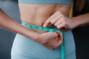Lady doing alpine ice hack fro weight loss and measuring the waist